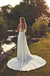 Abito da sposa ROSIE EDDY K con schiena scoperta, lungo strascico, in un giardino al tramonto.