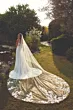 Abito da sposa ROSIE di Eddy K con lungo strascico e dettagli floreali, ambientato in un giardino al tramonto.
