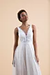 Abito da sposa girasole con corpetto in pizzo e gonna fluida, sfondo beige.