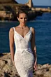 Abito da sposa in pizzo bianco JASPER di Mark Loren, scollo a V, sfondo marino.