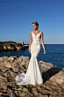 Abito da sposa JASPER di Mark Loren, elegante e aderente, su scogliera con mare e cielo blu sullo sfondo.