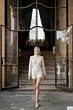 Abito da sposa corto in pizzo bianco, modello GIULIA di Sposae Atelier, indossato da una modella su gradini eleganti.