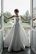 Abito da sposa elegante Alchiba di Sposae Atelier, donna in posa su balcone con vista giardino.