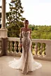 Abito da sposa PROCELLA - DAMA in pizzo floreale, spalle scoperte, su balcone con vista su giardino.