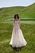 Abito da sposa boho SFUMATO - ARIAMO in pizzo bianco, sfondo prato verde e lago.