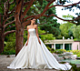 Abito da sposa Monoi Linea Sposae Atelier, elegante e raffinato, ambientato in un giardino rigoglioso.
