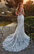 Abito da sposa Stacey di Eddy K con dettagli in pizzo, schiena scoperta e strascico, ambientato al tramonto.