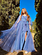 Abito lungo blu in tulle con maniche ampie, indossato all'aperto tra alberi verdi.
