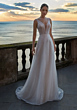 Abito da sposa EKATERINA con scollo a V, sfondo tramonto sul mare.