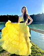 Abito lungo giallo con cintura nera indossato all'aperto vicino a un lago, modello HH580016 in saldo.