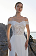 Abito da sposa L1067 Linea Oreasposa con corpetto in pizzo e scollo a spalle scoperte, sfondo naturale roccioso.