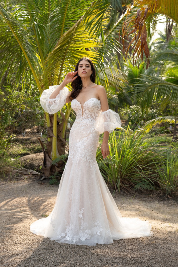 Abito da sposa Amelie Deluxe, modello sirena, con maniche trasparenti, in un giardino tropicale.