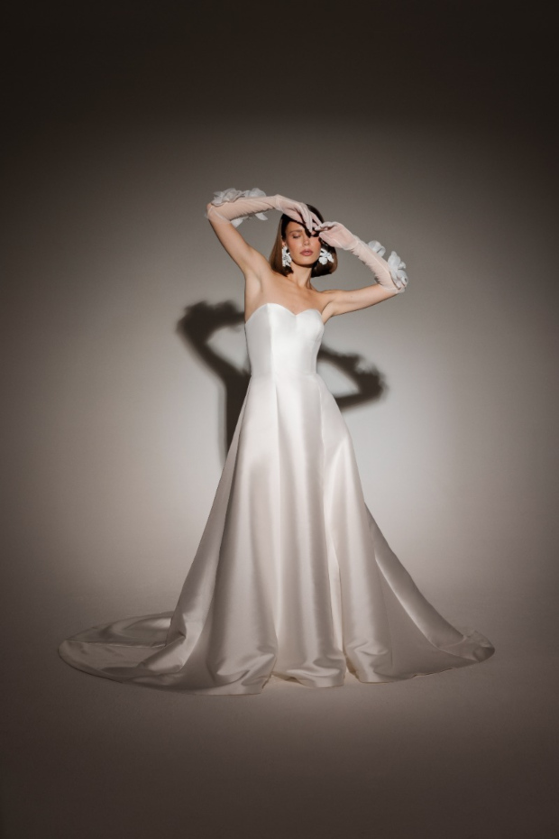 Abito da sposa bianco elegante, modello PARIGI di ESSENTIAL BY SPOSAE, senza spalline, con guanti trasparenti decorati.