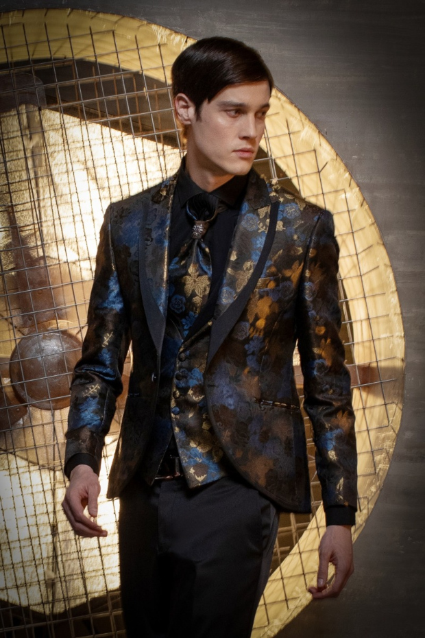 Abito da uomo elegante con giacca floreale blu e oro, sfondo industriale.