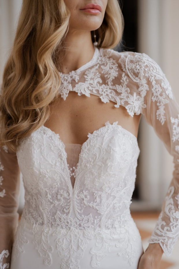 Abito da sposa in pizzo bianco con dettagli floreali, maniche lunghe trasparenti, modello ISMAELE di Romantica by Sposae.