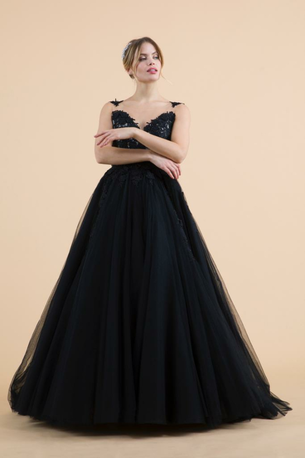 Abito da sera nero Dulcamara con dettagli in pizzo, indossato da modella su sfondo beige.