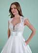 Abito da sposa CORINTIA in pizzo floreale con scollo a cuore e gonna ampia, sfondo verde.