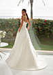 Abito da sposa LYLA St. Patrick, elegante e moderno, con sfondo di giardino e mare.