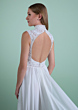 Abito da sposa PHIGALIA in pizzo bianco con schiena scoperta e colletto alto, sfondo verde.