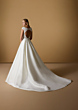 Abito da sposa ZETIAN Nicole Milano, schiena scoperta, gonna lunga, sfondo beige.