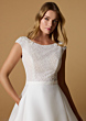 Abito da sposa ZETIAN di Nicole Milano, corpetto ricamato, gonna fluida, sfondo beige.