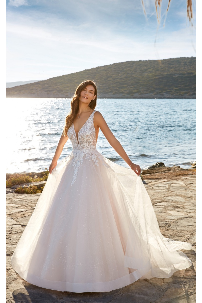 Abito da sposa Paulina Eddy K, scollo a V, dettagli in pizzo, sfondo mare e sole.