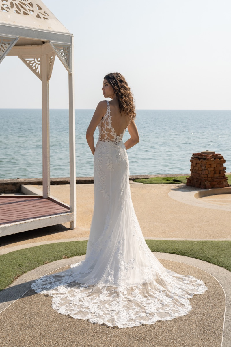 Abito da sposa Amelie Deluxe con schiena scoperta, pizzo floreale, sullo sfondo del mare.