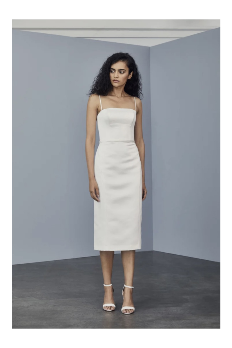Abito bianco Lw163 linea Amsale, spalline sottili, lunghezza midi, indossato da modella su sfondo grigio chiaro.