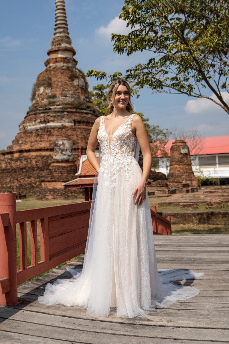 Abito da sposa Amelie 20317 in pizzo bianco davanti a tempio antico, atmosfera romantica ed elegante.