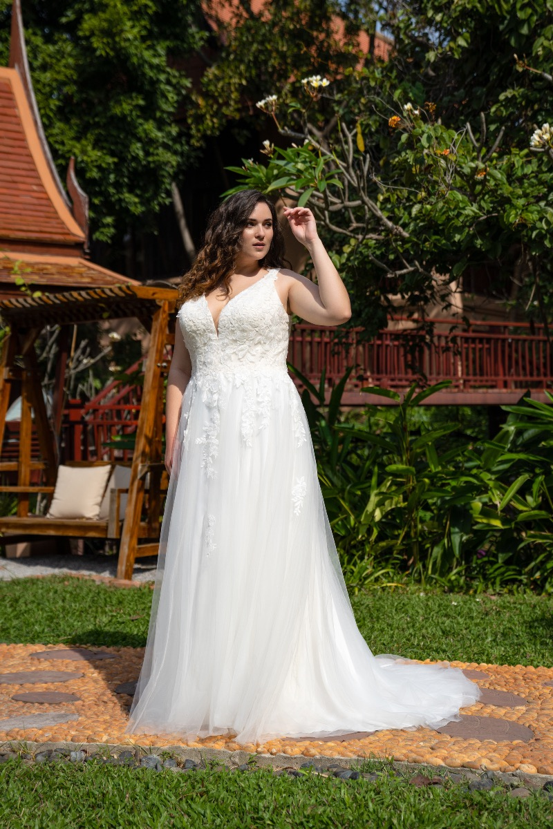 Abito da sposa Bella by Amelie 30116W, modello in pizzo bianco, in giardino con gazebo in legno.