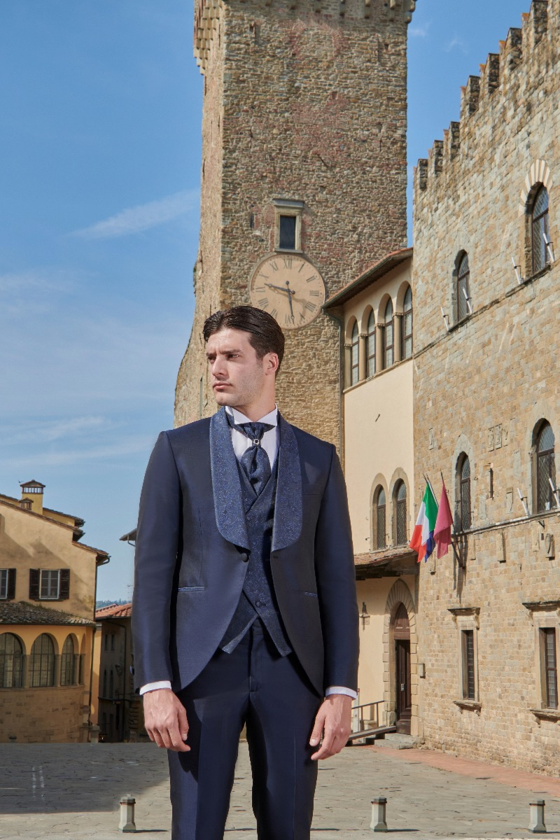 Abito elegante Rocchini 31 indossato da uomo in piazza storica con torre e orologio.