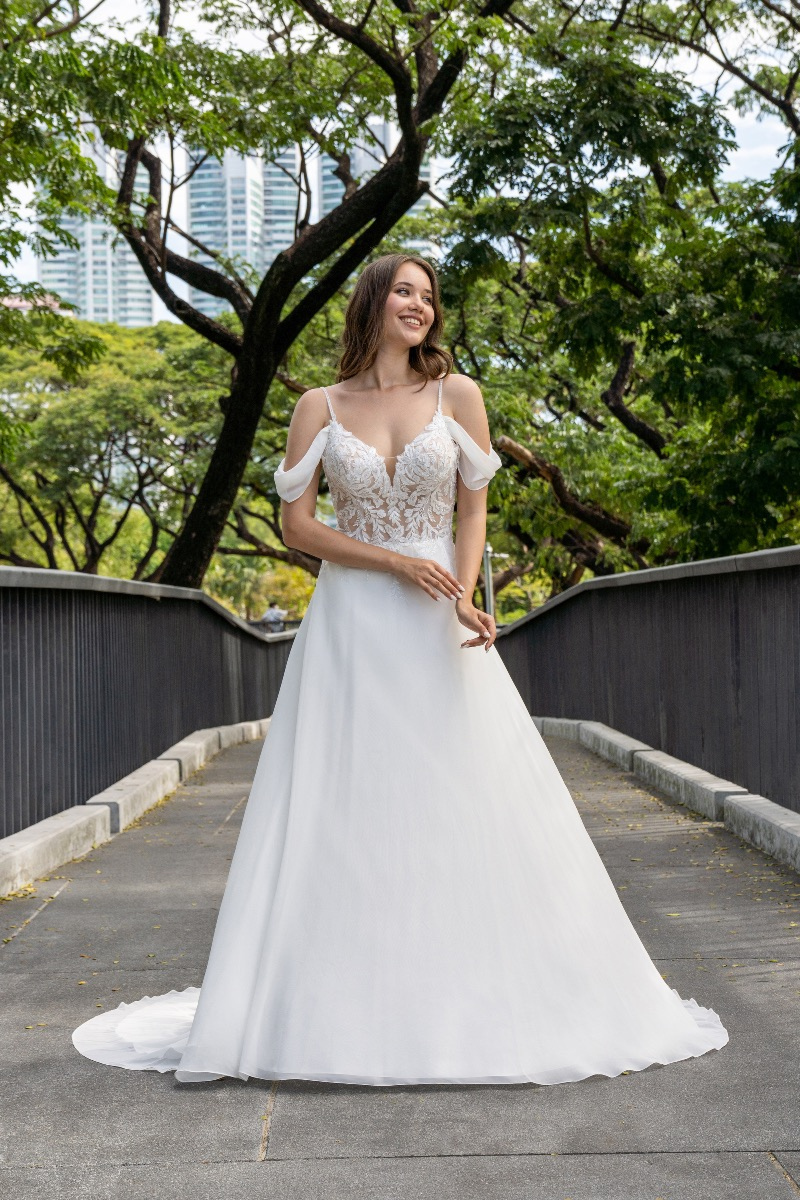 Abito da sposa elegante SAYES BY AMELIE in un parco, con dettagli in pizzo e spalline sottili.
