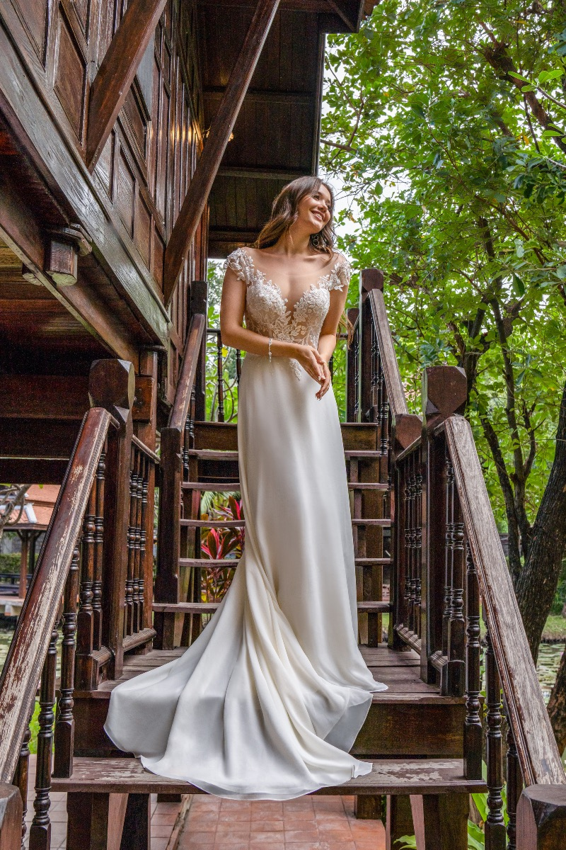 Abito da sposa SAYES BY AMELIE 40071, elegante, con dettagli in pizzo, su scala di legno in ambiente naturale.