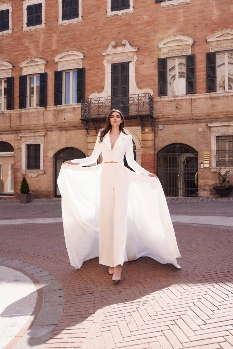 Modella con giacca bianca L7022 Linea Mark Loren, sfondo architettura storica.