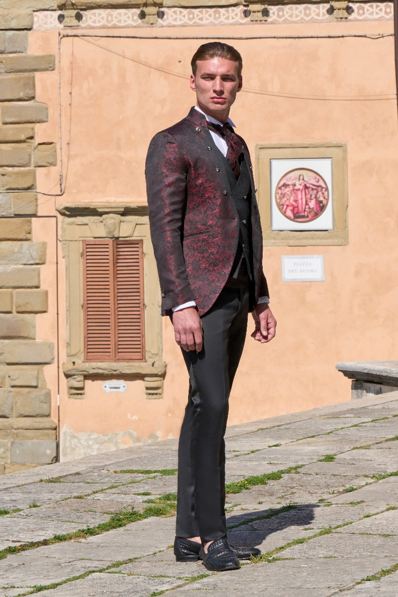 Abito elegante Rocchini 55 uomo, giacca rossa e nera, pantaloni neri, sfondo architettura storica.