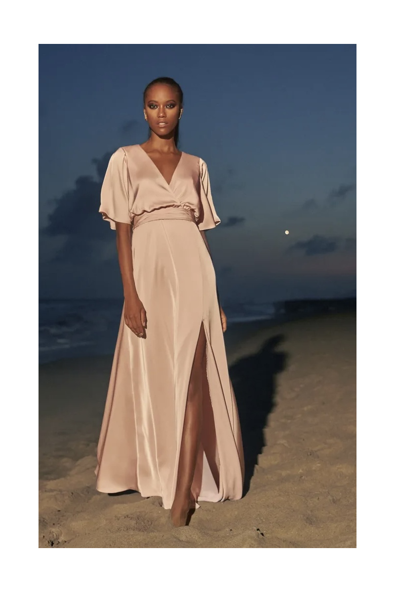 Abito ESSENTIAL 2261 Pronovias, elegante e fluido, indossato su spiaggia al tramonto.