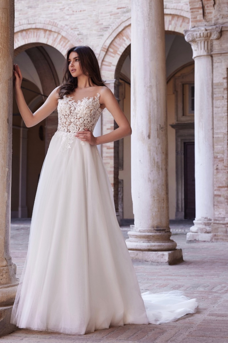 Abito da sposa I48822 Mark Loren, corpetto in pizzo floreale, gonna in tulle, ambientazione architettonica.