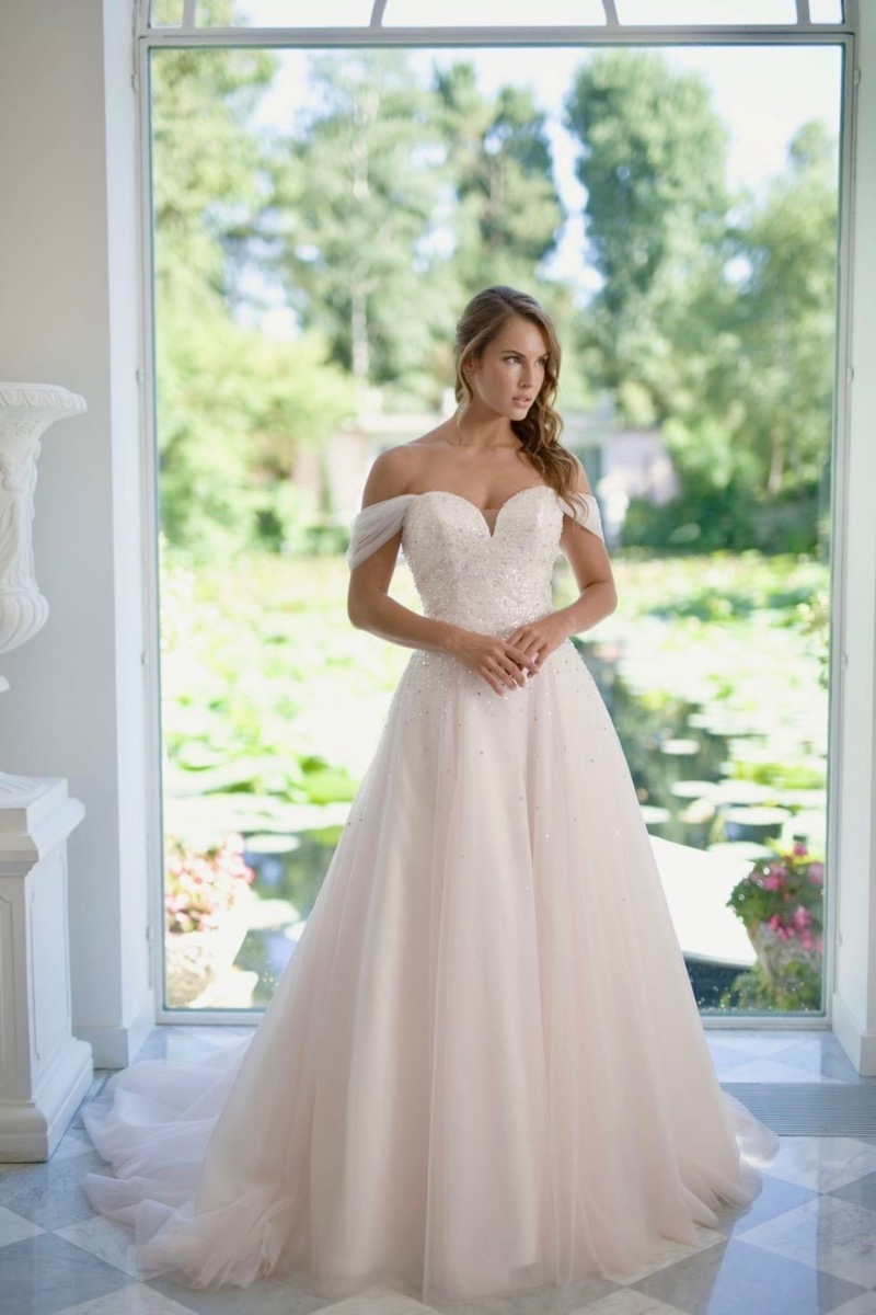 Abito da sposa Elena Linea, scollo a cuore, spalle scoperte, sfondo verde naturale.