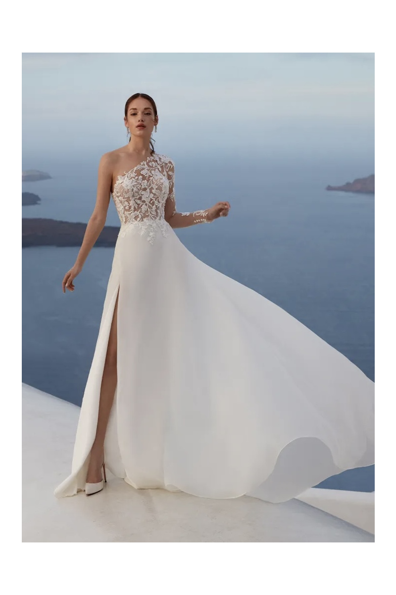 Abito da sposa Linosa Nicole Jolies, monospalla in pizzo, sfondo mare, elegante e sofisticato.