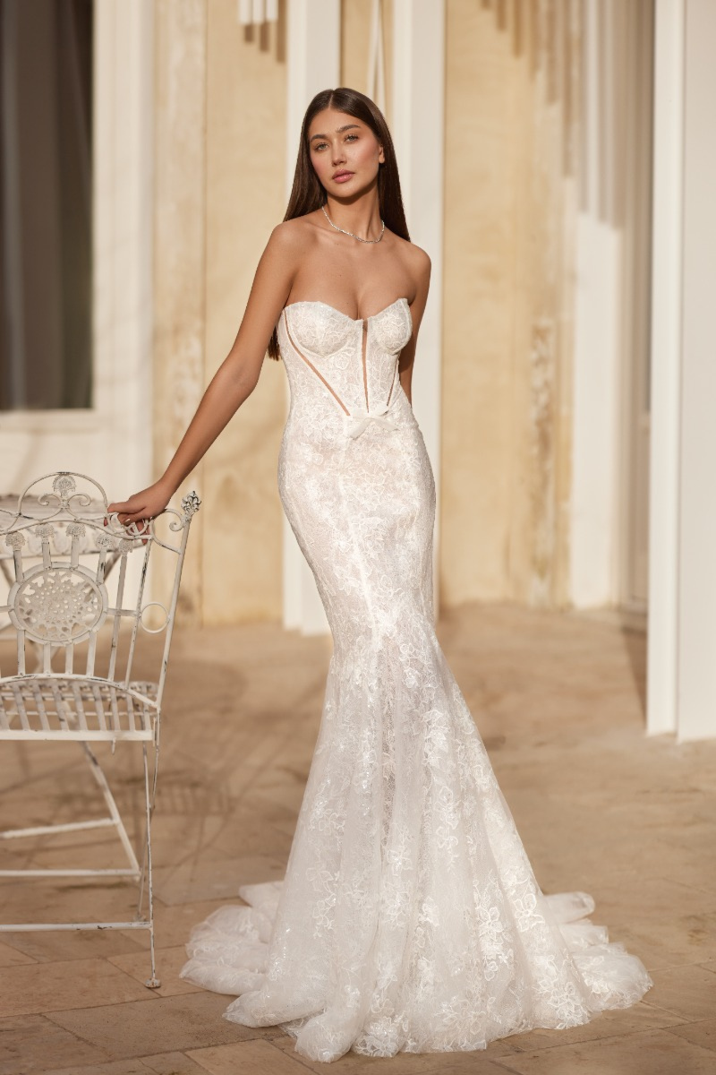 Abito da sposa AGATE di Mark Loren, design elegante in pizzo, sfondo architettonico raffinato.