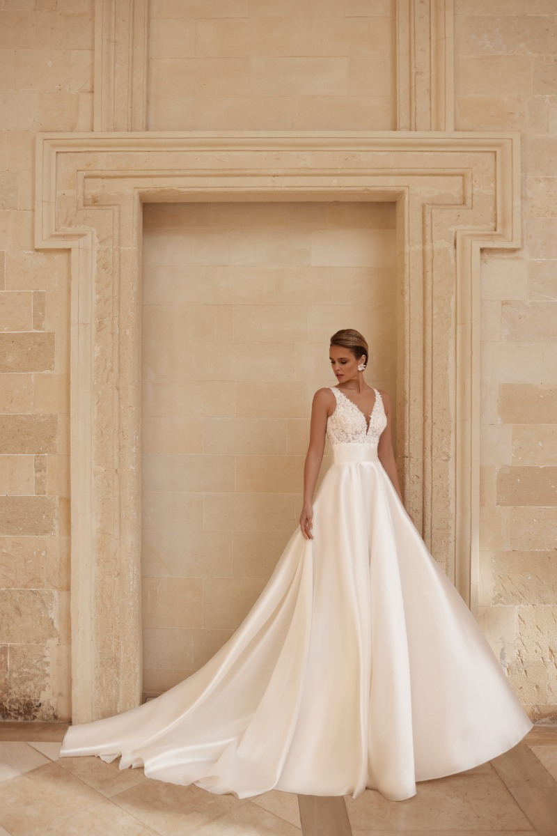 Abito da sposa Amethyst di Mark Loren, elegante design in pizzo e seta, sfondo architettonico classico.