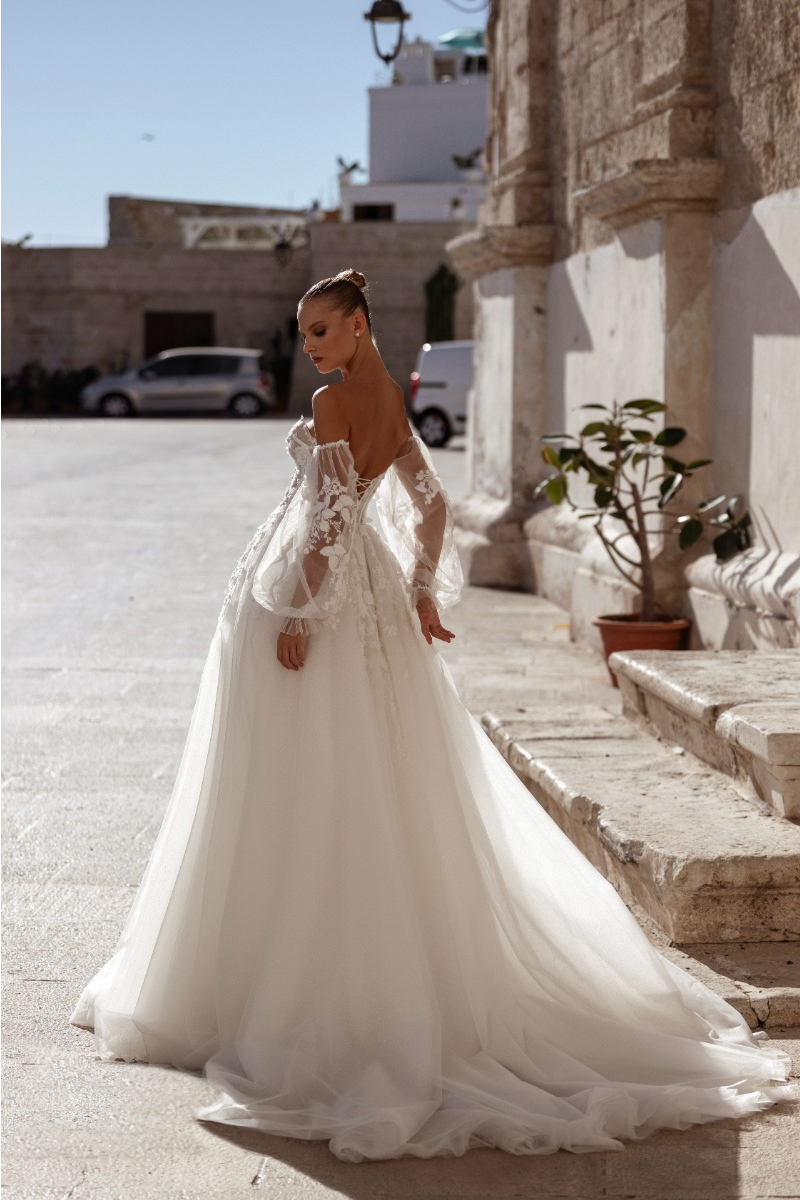 Abito da sposa ANTHURIUM di MADIONI, elegante con dettagli in pizzo, indossato in un contesto urbano.