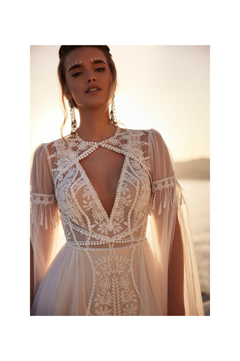 Abito da sposa ANWAR - DAMA, dettagli in pizzo, scollo a V, maniche trasparenti, sfondo tramonto.