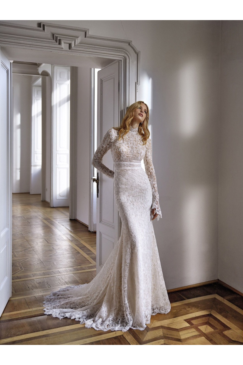 Abito da sposa in pizzo bianco ARANYA in interni eleganti con luce naturale.