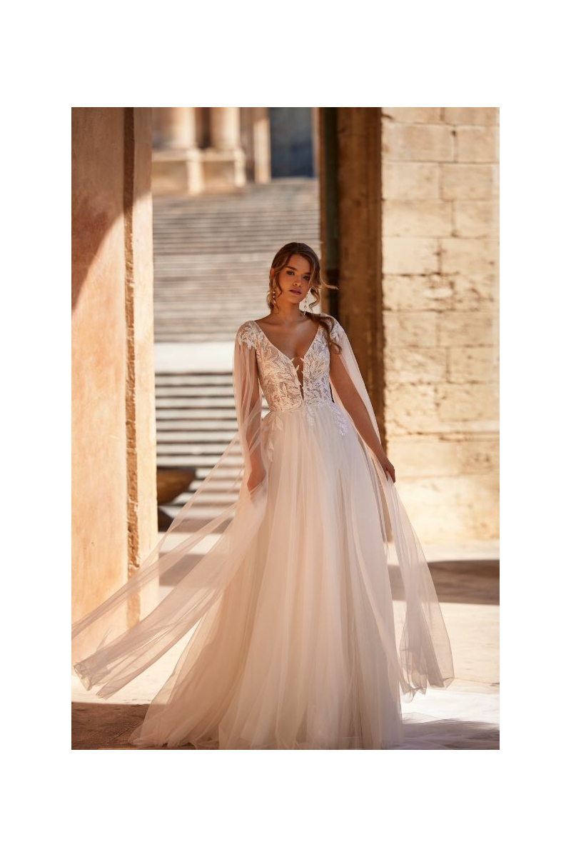 Abito da sposa AVA - DAMA in pizzo e tulle, con scollo a V, maniche lunghe trasparenti, in ambientazione elegante.
