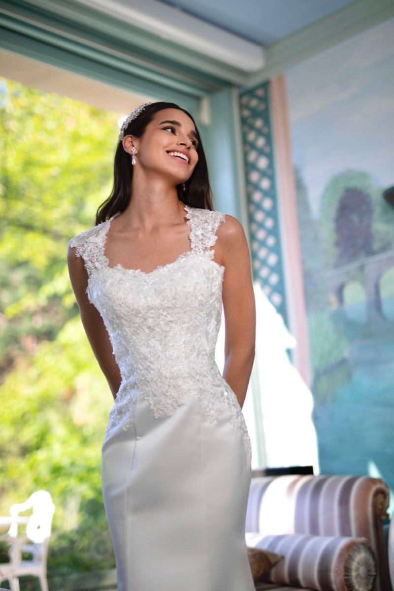 Abito da sposa elegante con dettagli in pizzo di Rea Linea Sposae Atelier, indossato da modella sorridente.