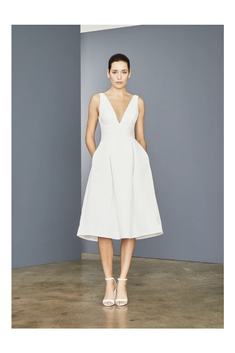 Abito bianco Amsale Lw152, lunghezza midi, scollatura a V profonda, modello elegante su sfondo grigio.