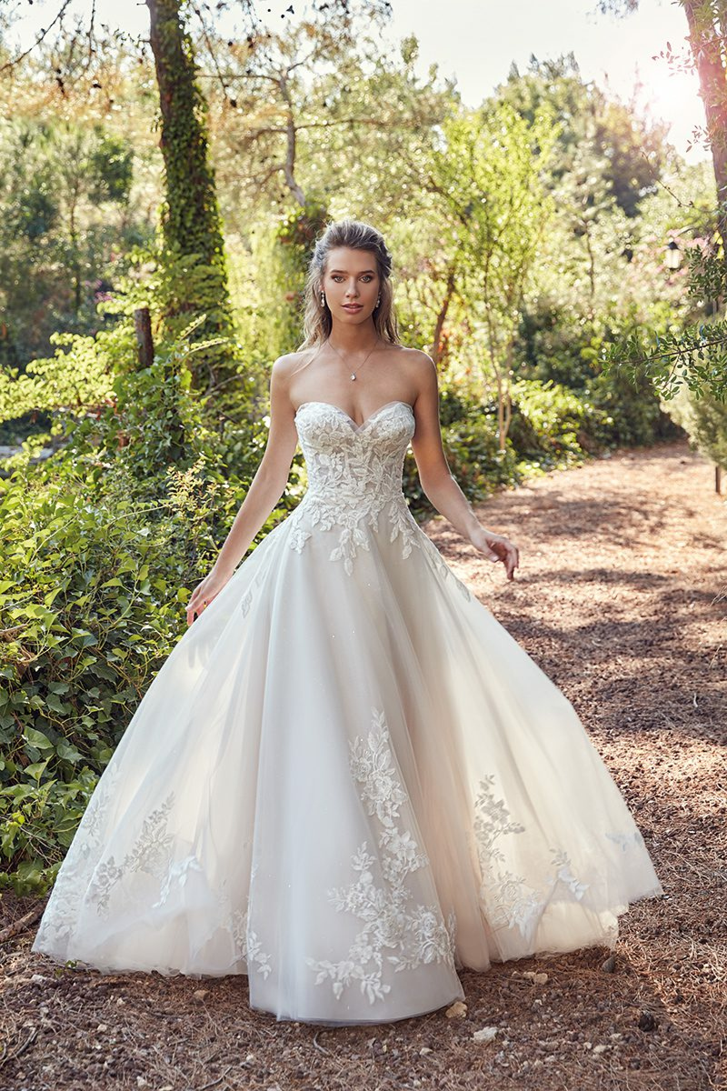 Abito da sposa Scarlet Eddy K in pizzo floreale, scollo a cuore, ambientato in un giardino soleggiato.