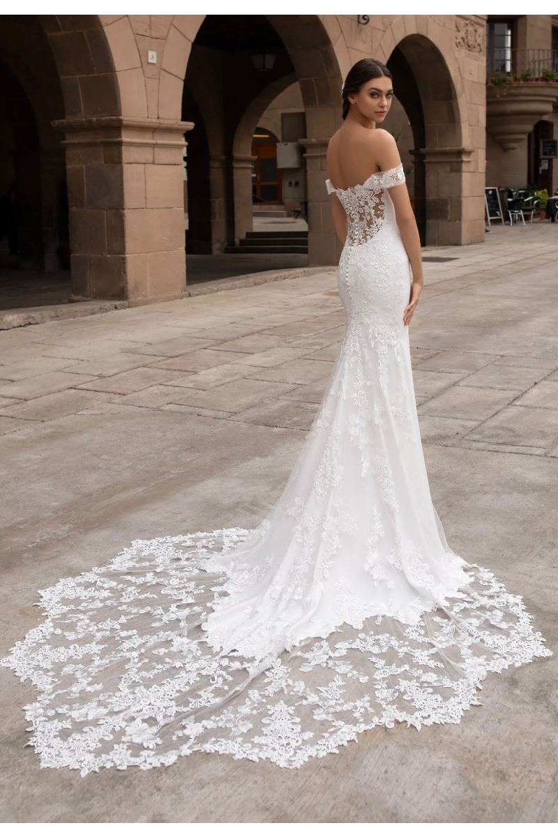 Abito da sposa Pronovias Syrinix con dettagli in pizzo, spalle scoperte e lungo strascico elegante.