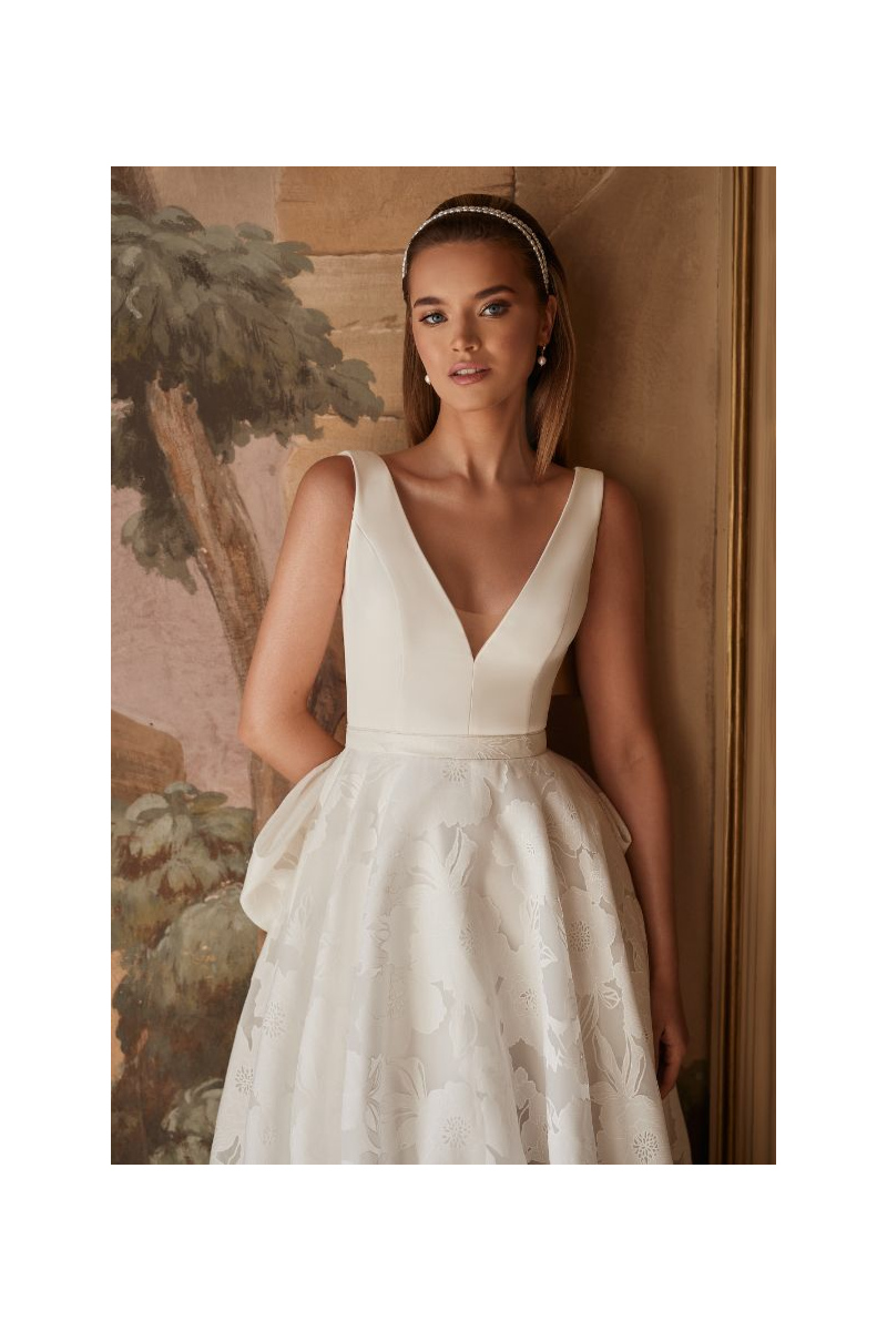 Abito da sposa CHARLOTTE - DAMA con scollo a V e gonna floreale, indossato da modella in ambientazione elegante.
